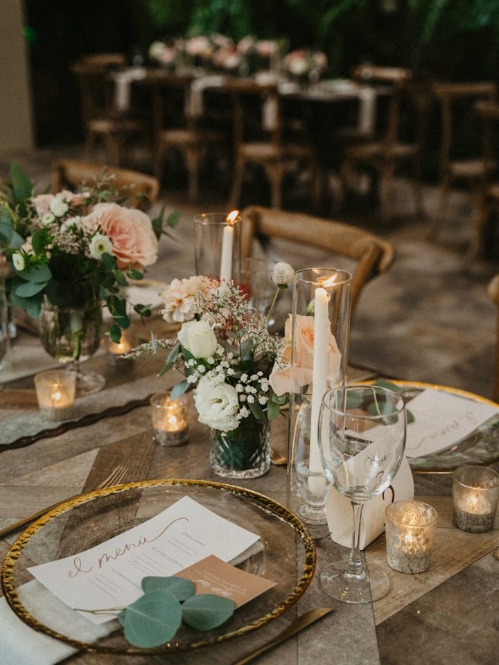 Elegant gedeckter Hochzeitstisch mit Blumen, Kerzen und Platzkarten in einem festlichen Ambiente.